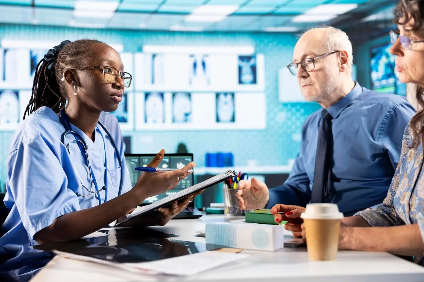 Девушка-медсестра встречается с пожилой парой в кабинете, чтобы изучить результаты рентгеновского исследования.